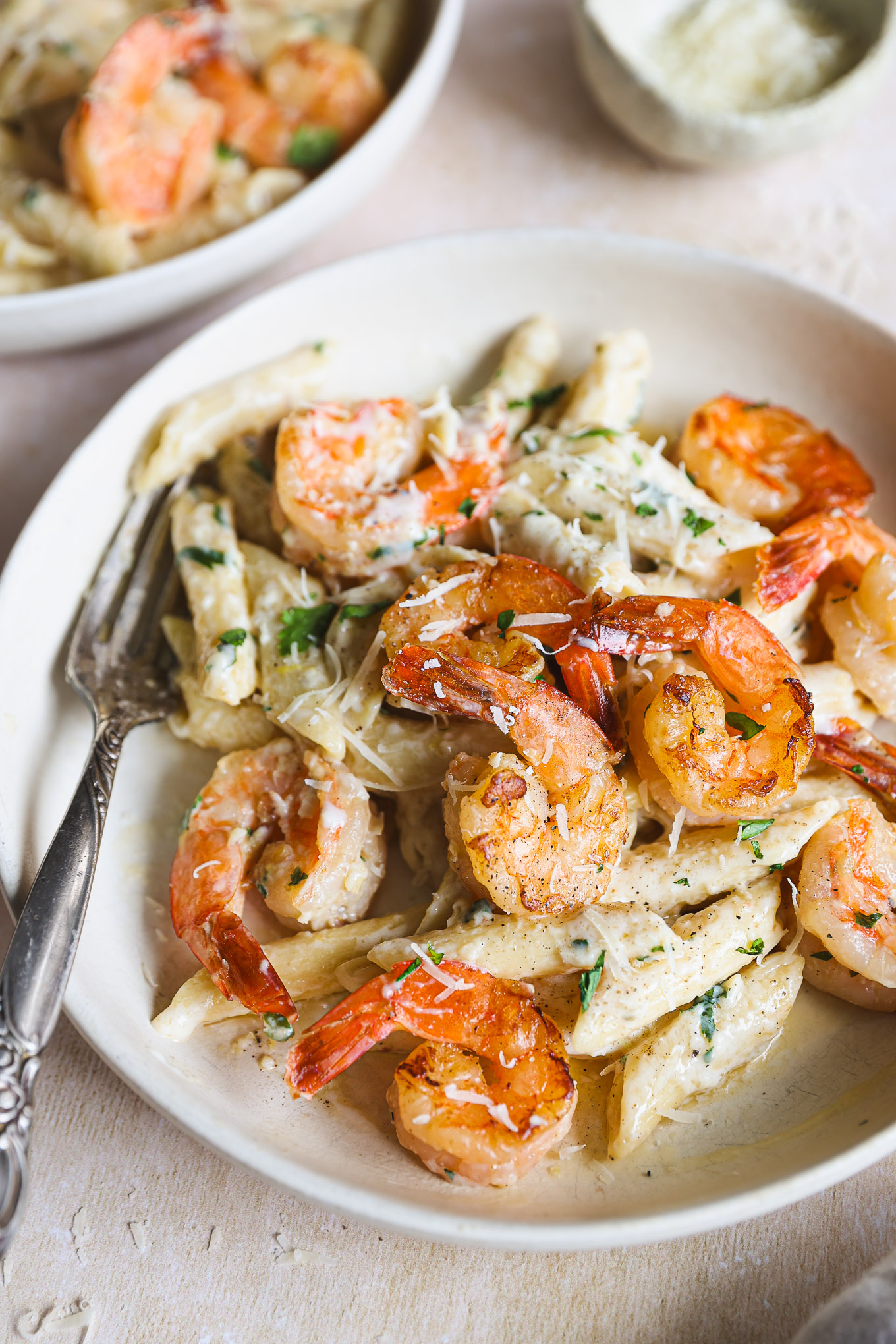 close up lemon and shrimp pasta on a plate with a side of fork.