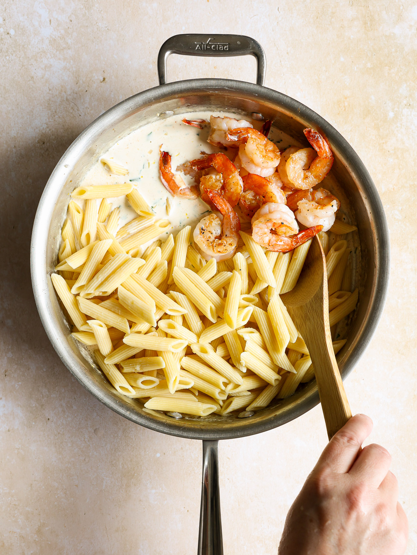 penne pasta and cooked shrimp in cream sauce in saucepan.