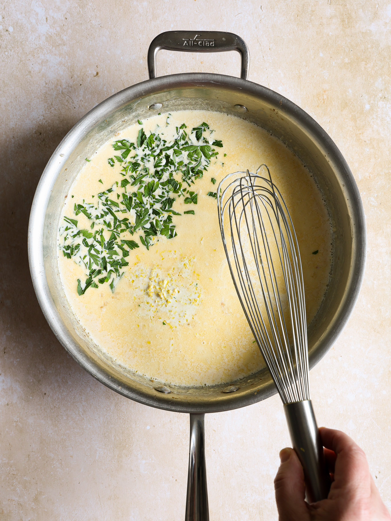 lemon cream sauce with parsley in a saucepan.