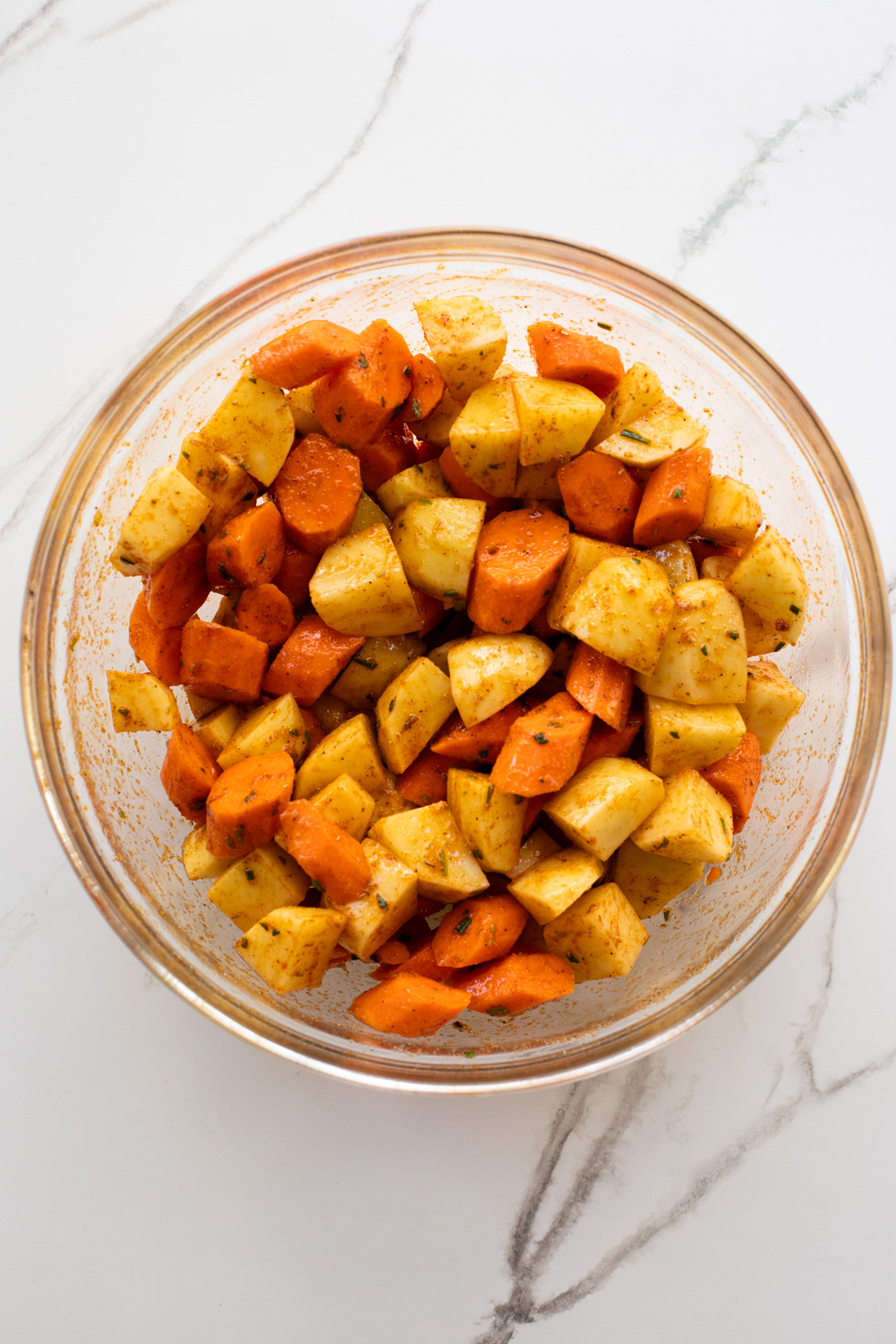 mixed potatoes and carrots with spices in a bowl.