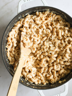 whole wheat mac and cheese in a dutch oven with a wooden spoon.