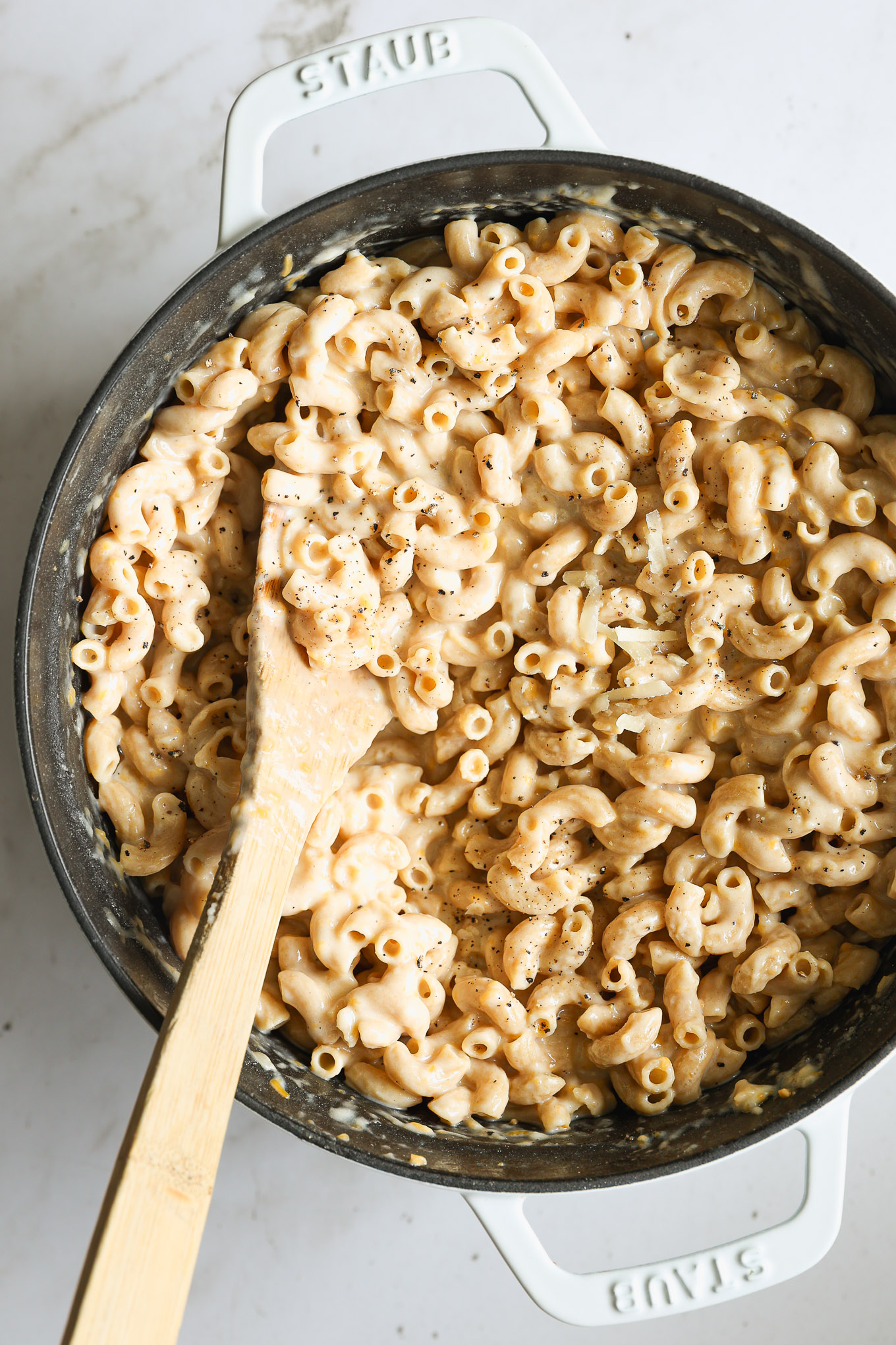whole wheat mac and cheese in a dutch oven with a wooden spoon.