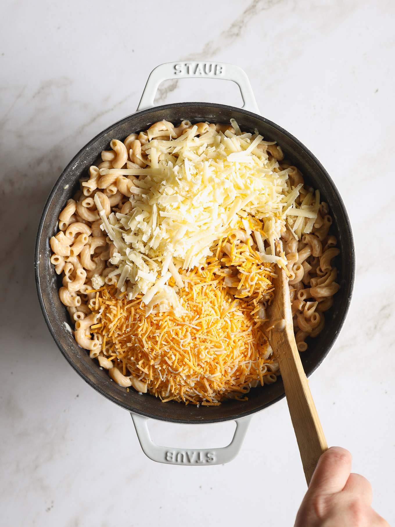 shredded cheese over cooked macaroni.