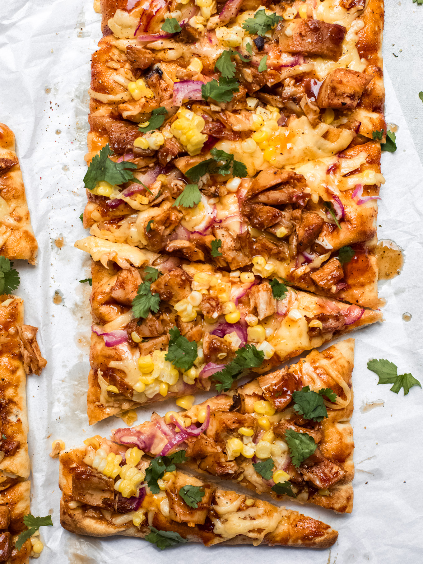 bbq chicken flatbread on white parchment paper.