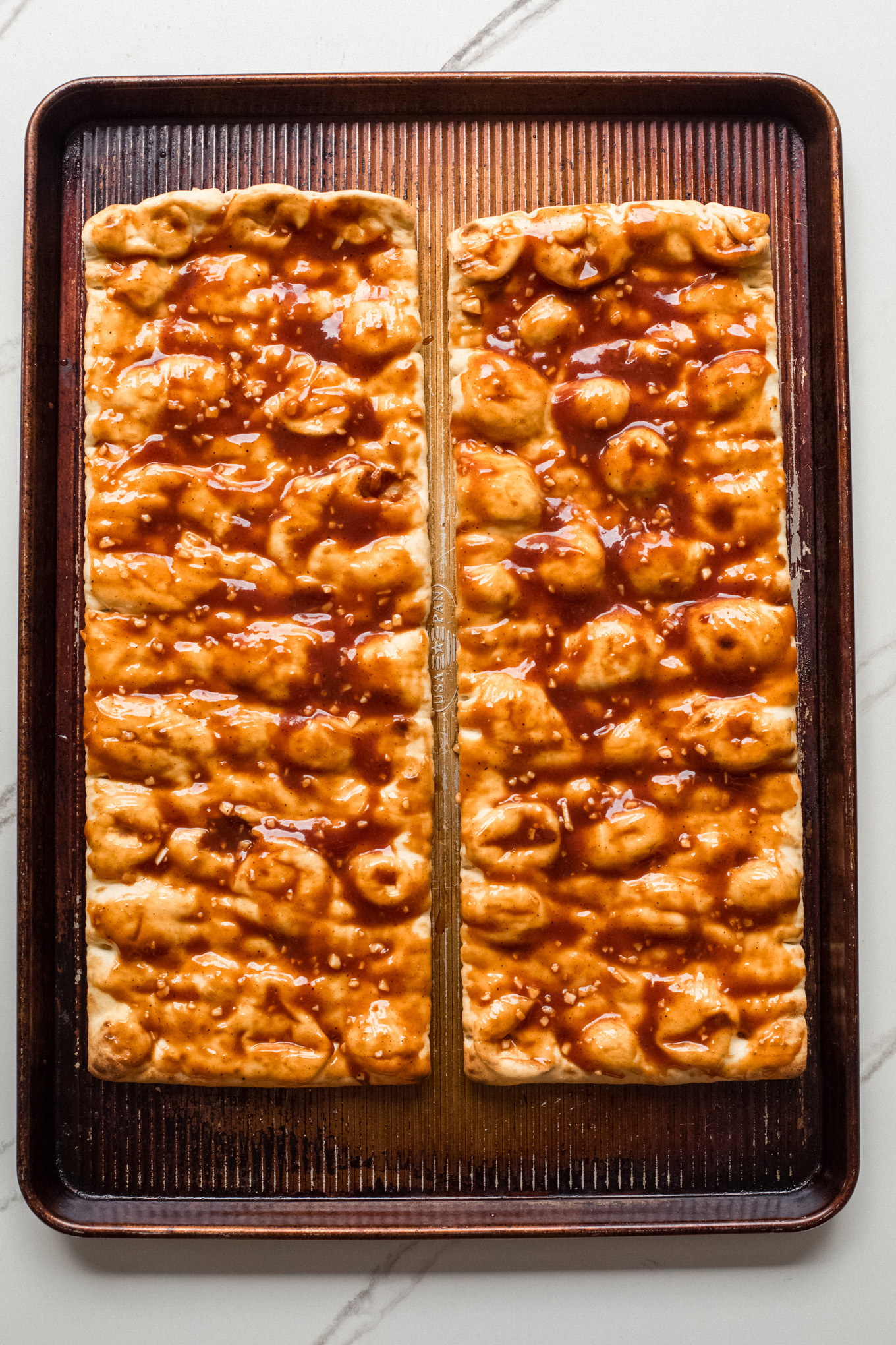 flatbread on baking sheet covered in bbq sauce.