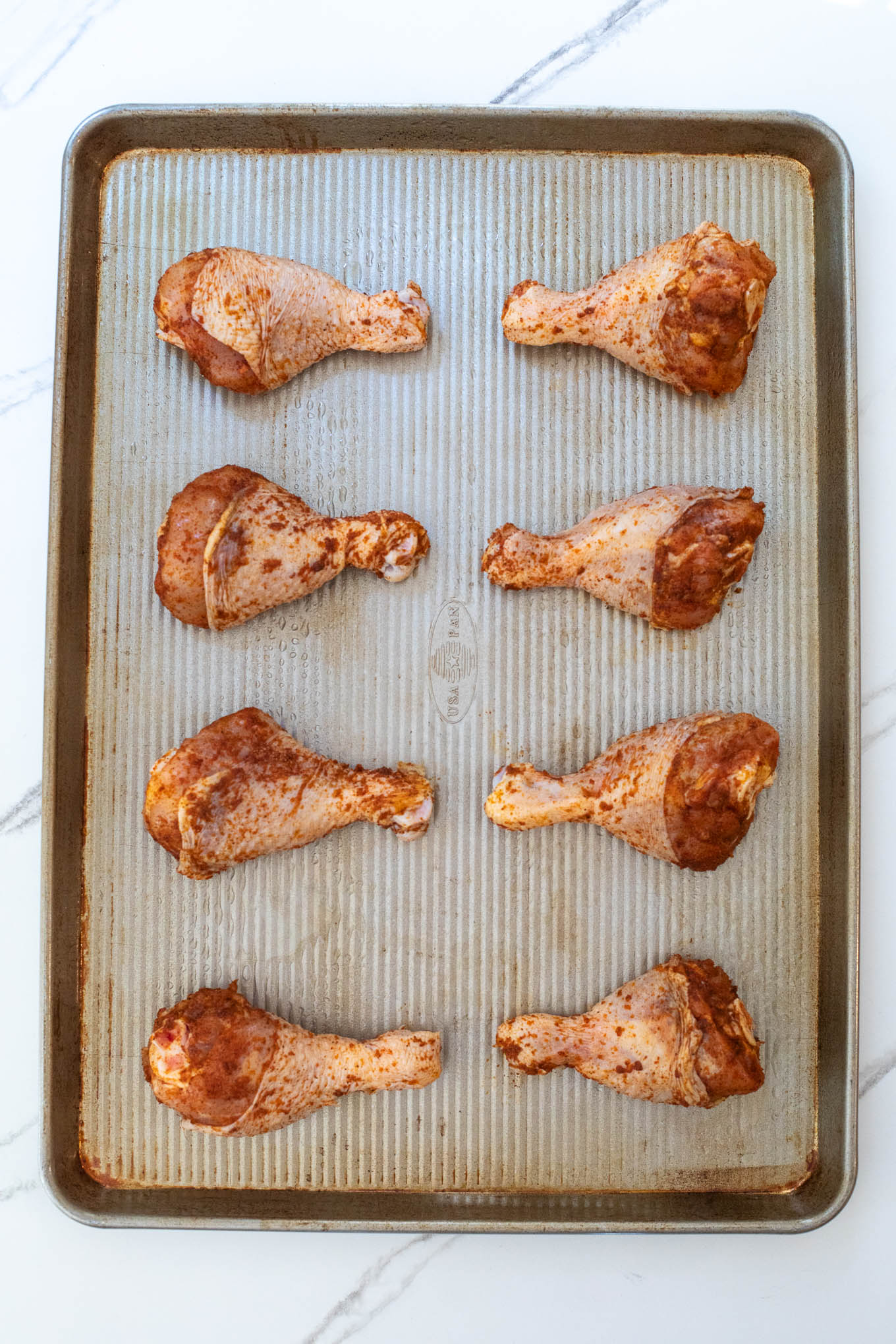 seasoned drumsticks on a sheet pan.