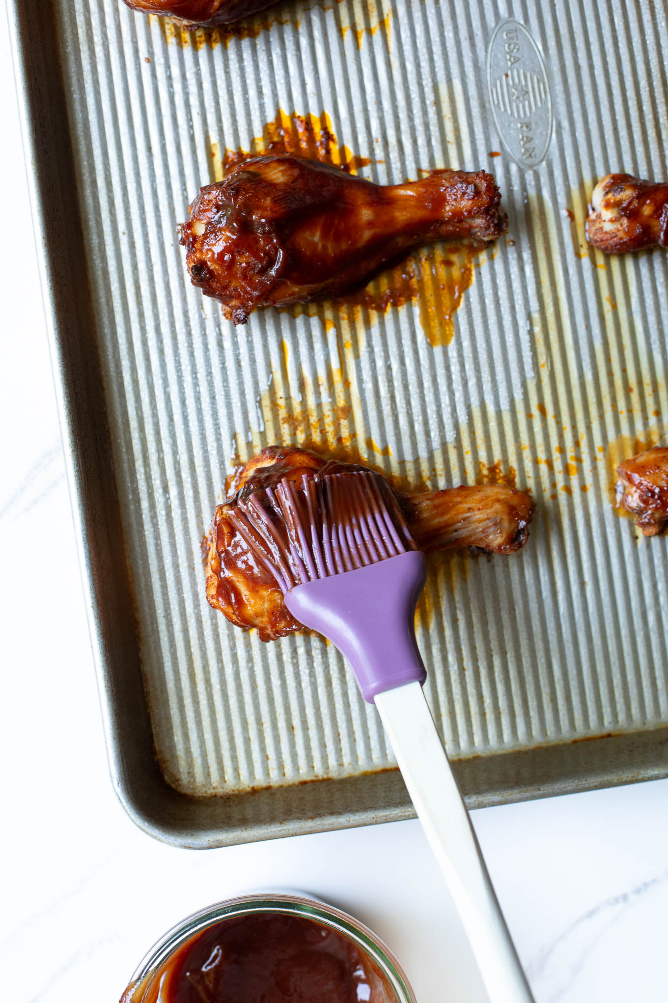 close up roasted drumstick being brushed with BBQ sauce.