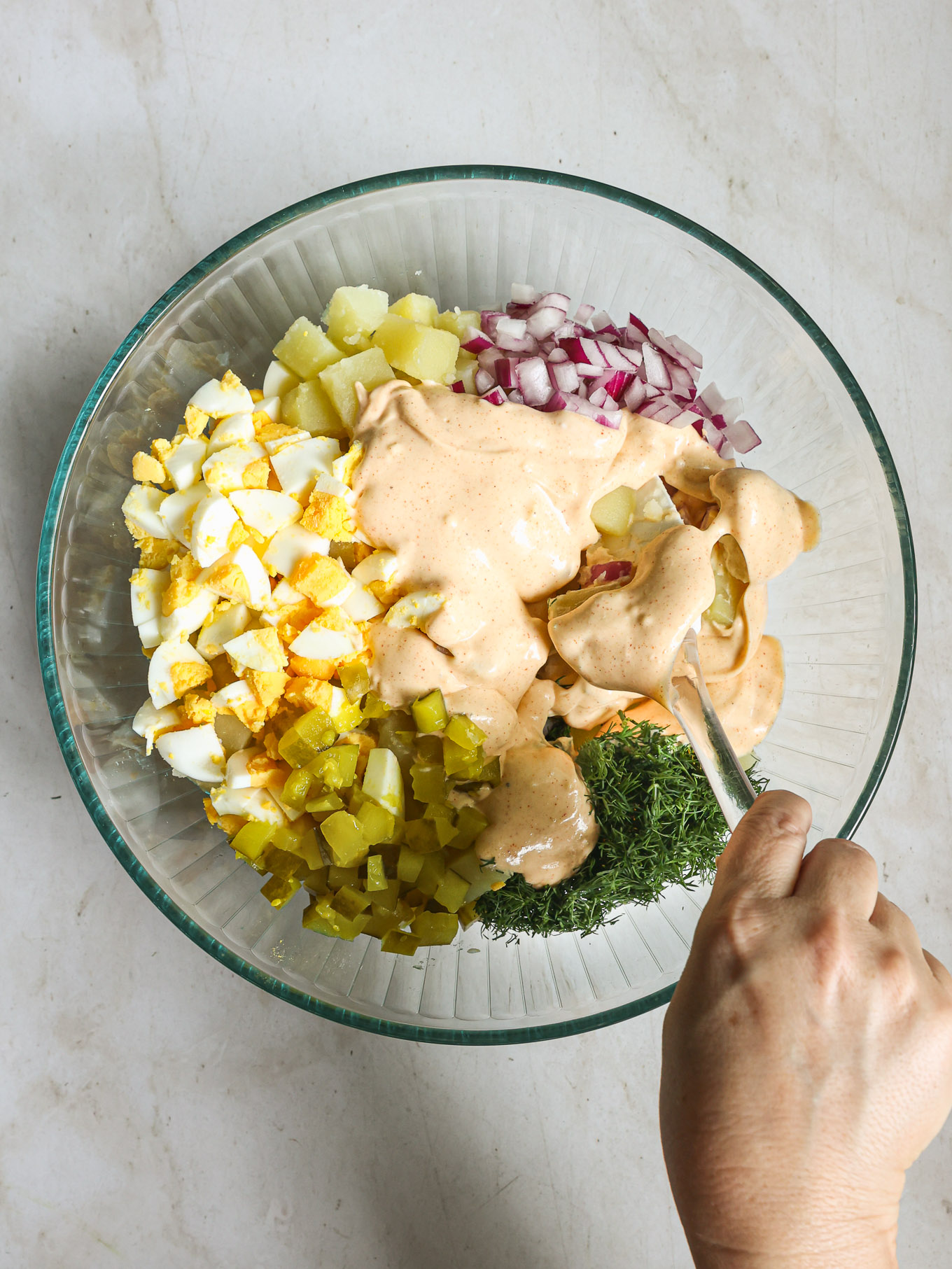chopped up potato salad ingredients in a glass bowl.