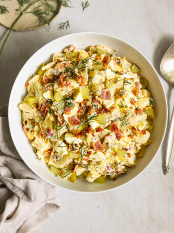 potato salad with bacon in a white bowl.
