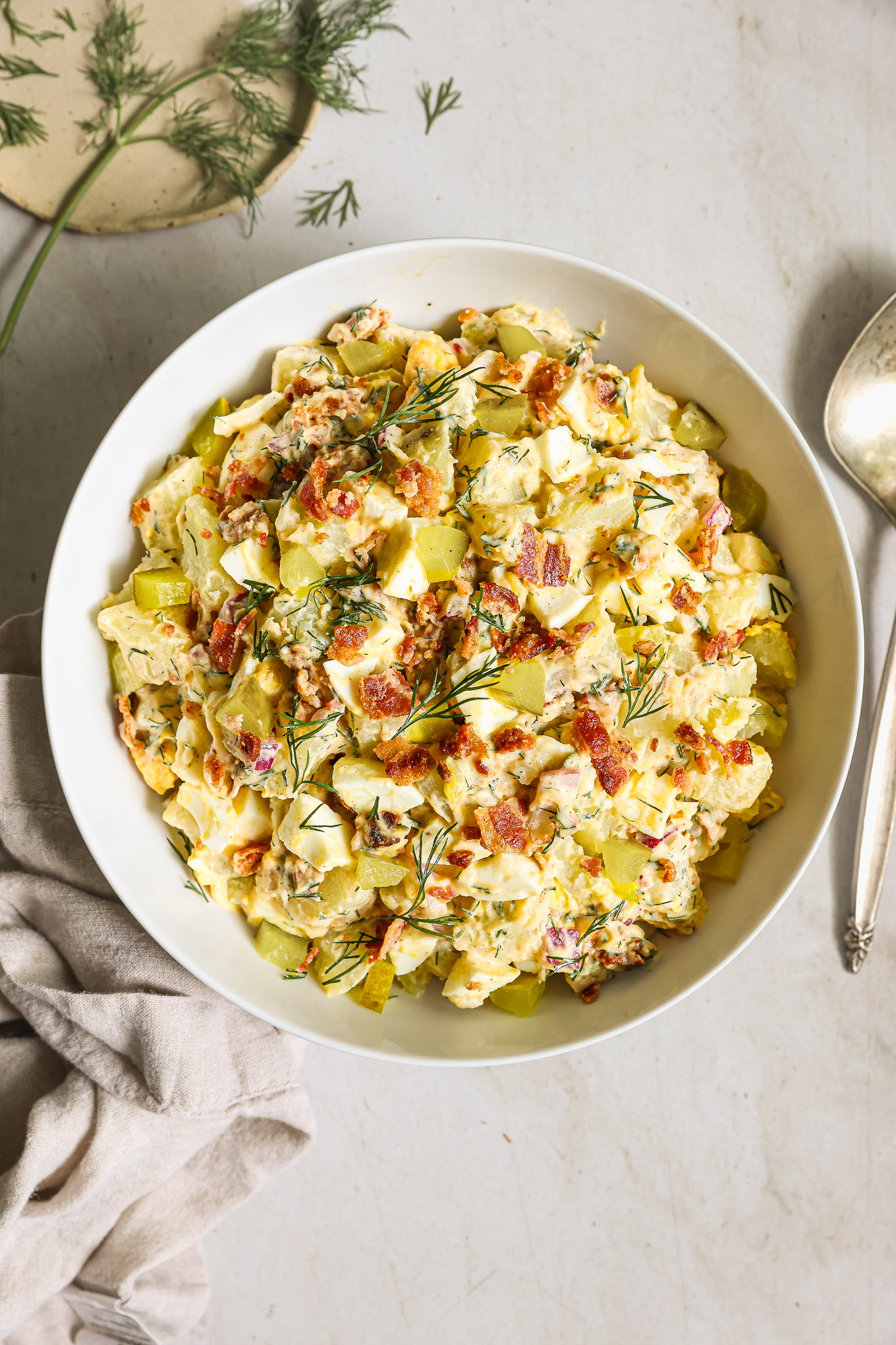 potato salad with bacon in a white bowl.