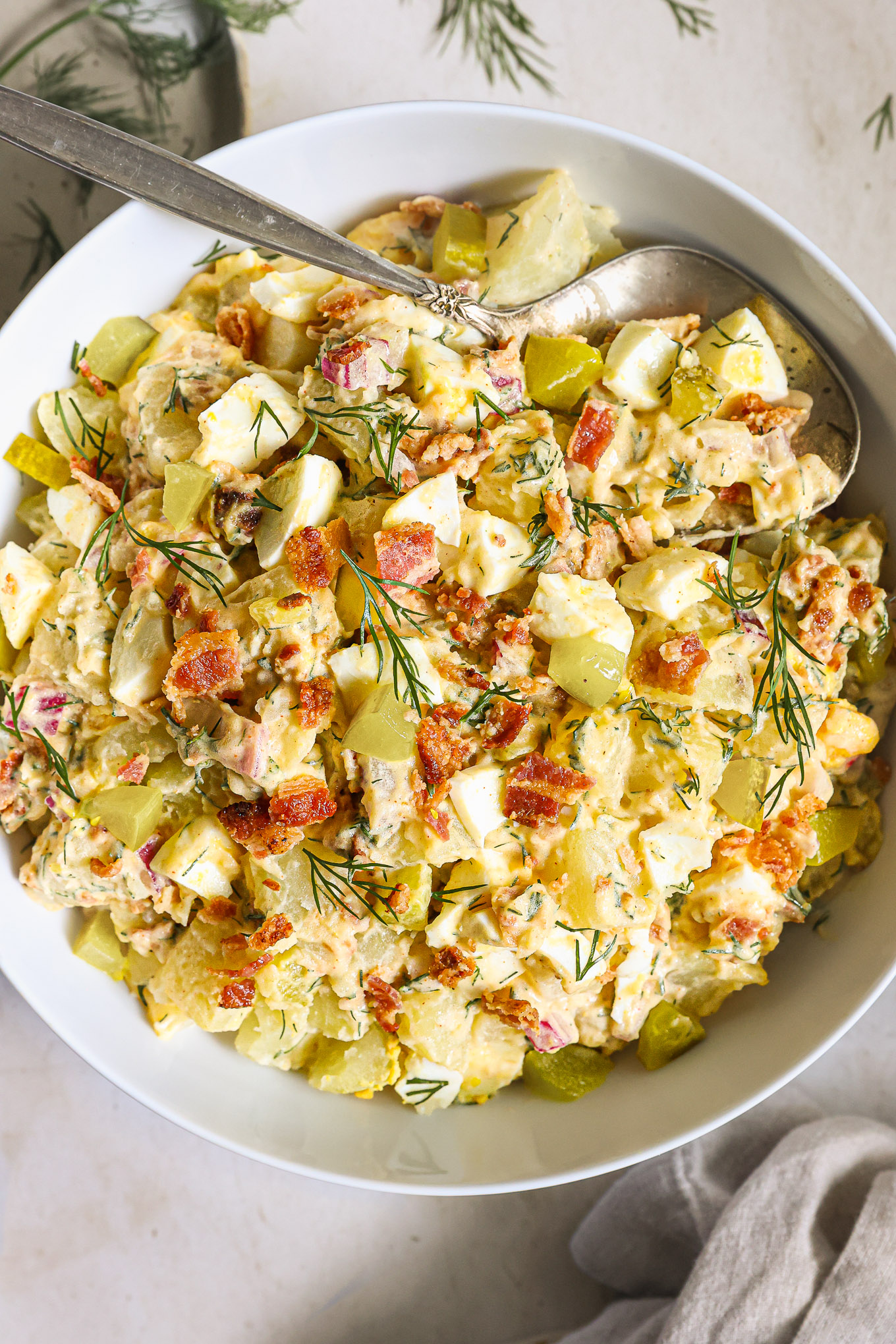 close up potato bacon salad garnished with bacon.
