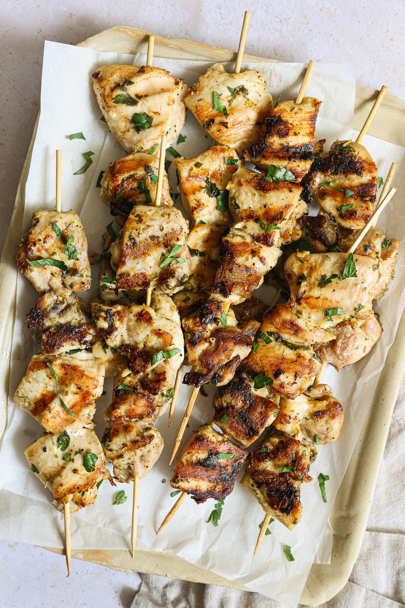 close up grilled chicken skewers on a white platter.