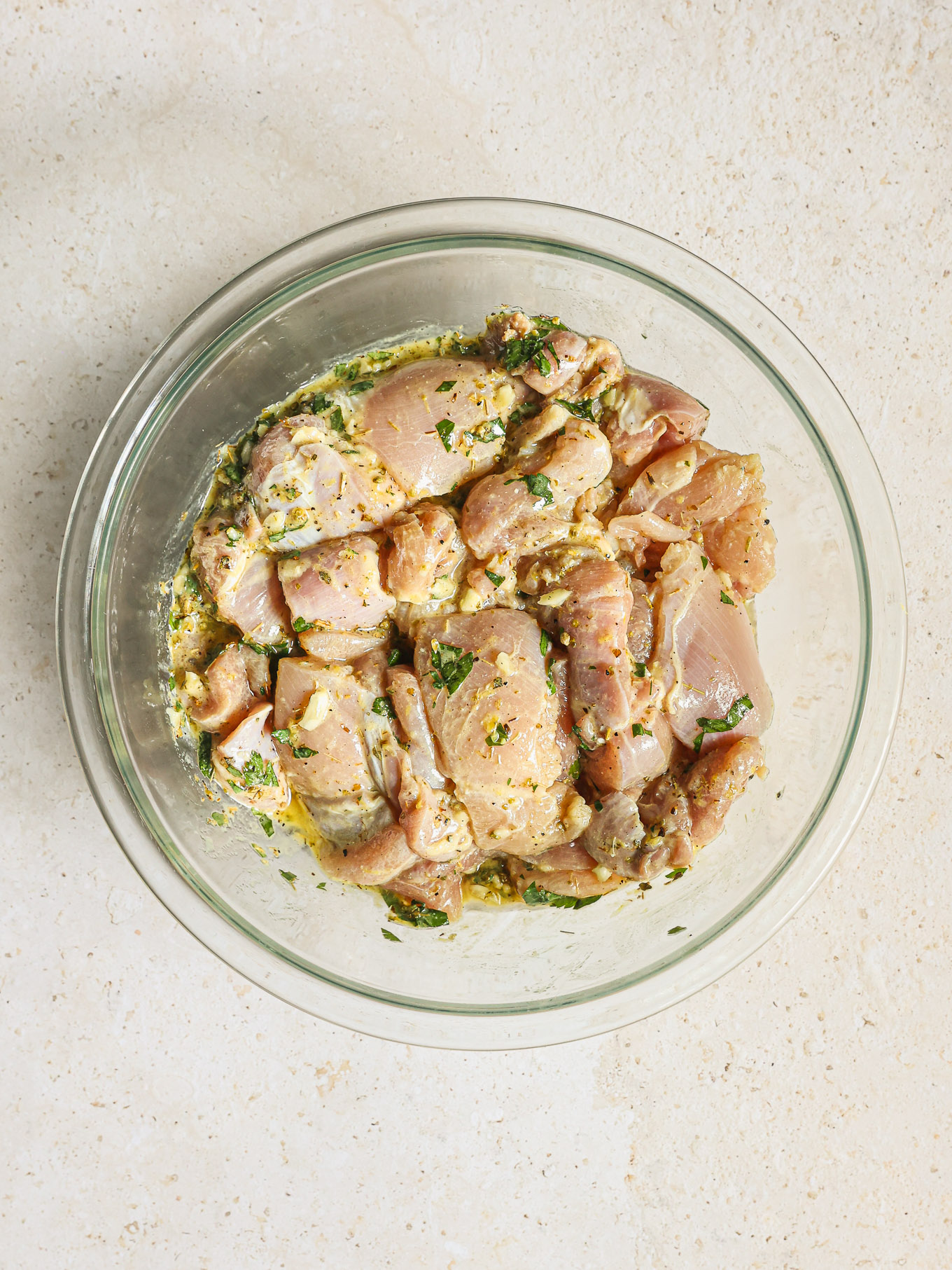 chicken in a glass bowl covered in marinade.