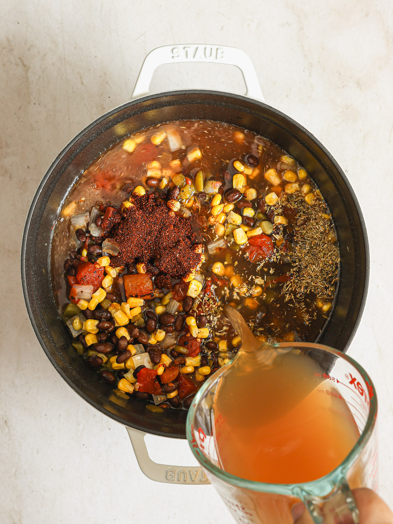 vegetables with spices and stock in a dutch oven.