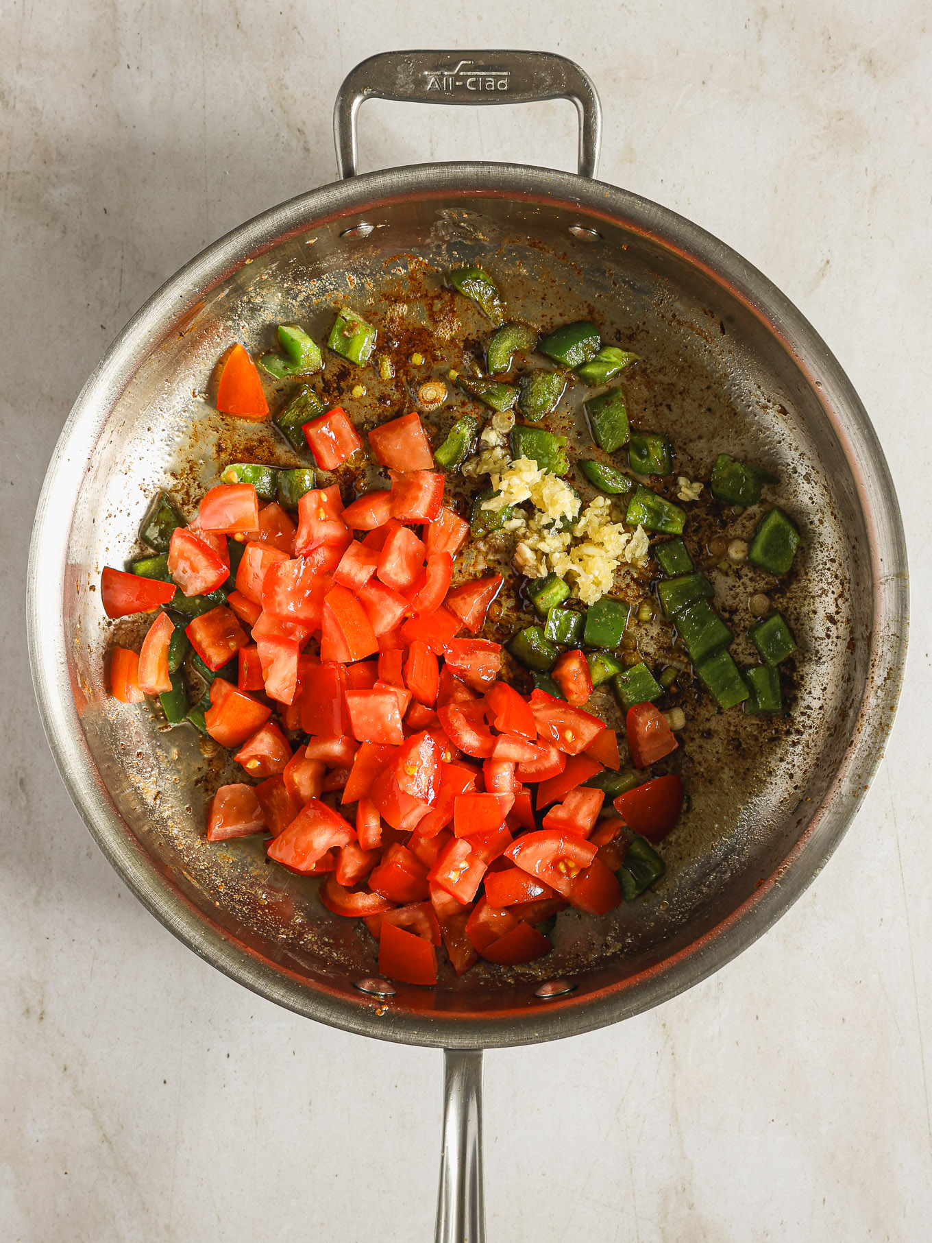 diced tomatoes with bell peppers and garlic in a saute pan.