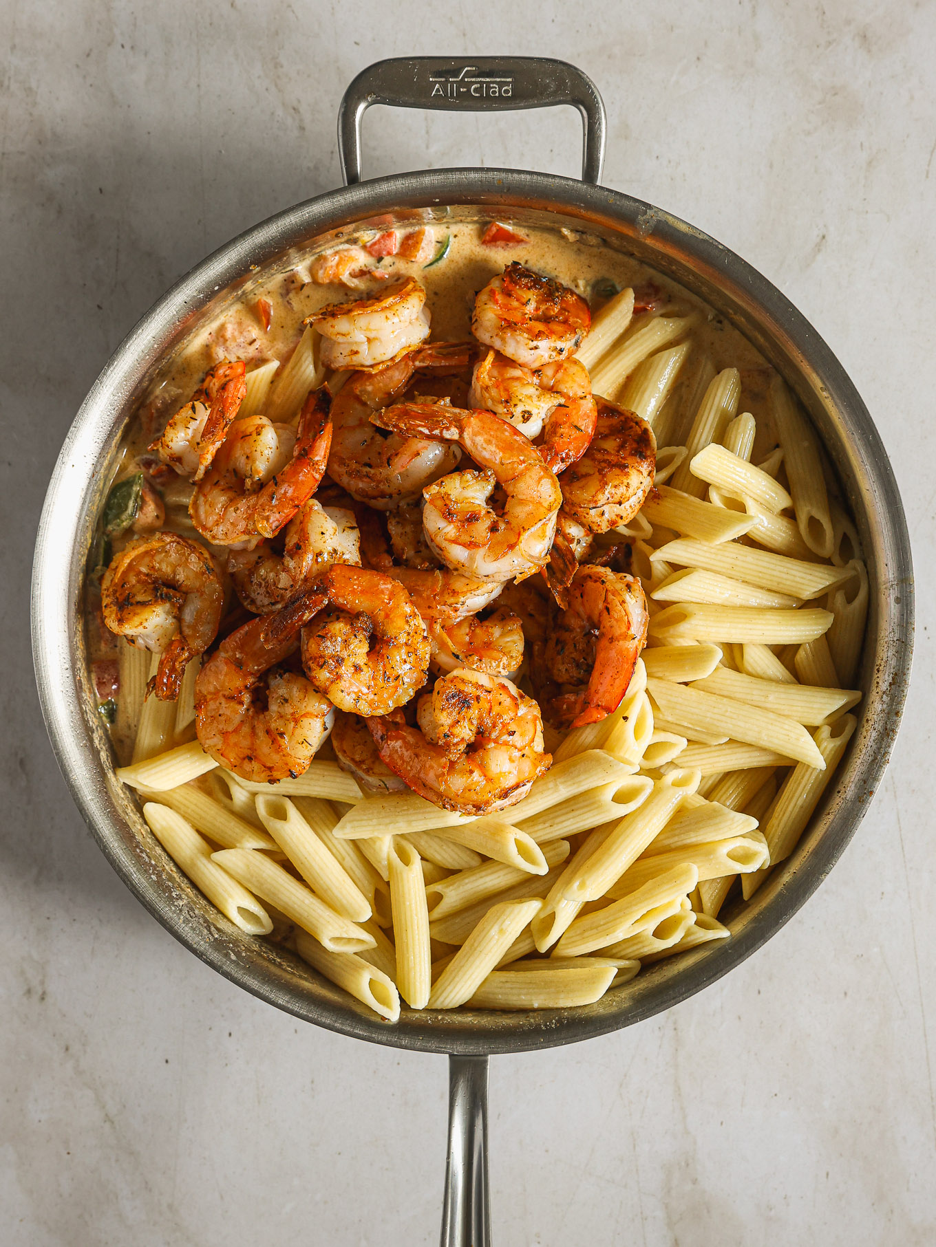 cooked penne with shrimp in a saute pan.