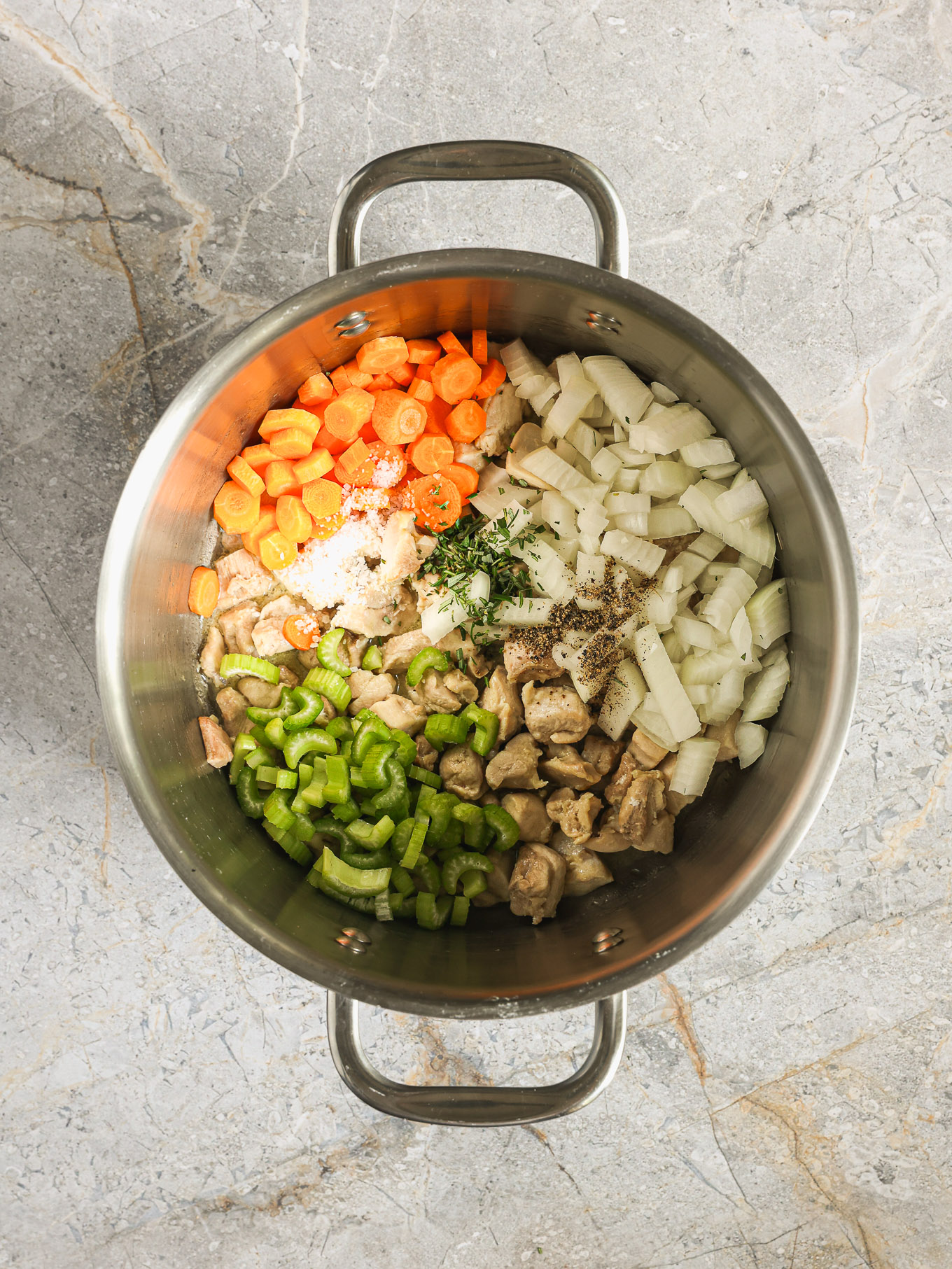 carrots, onions, and celery with cooked chicken in a pot.