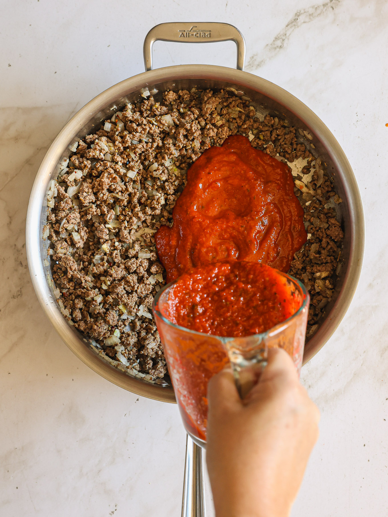 cooked ground beef with marinara sauce in a saute pan.