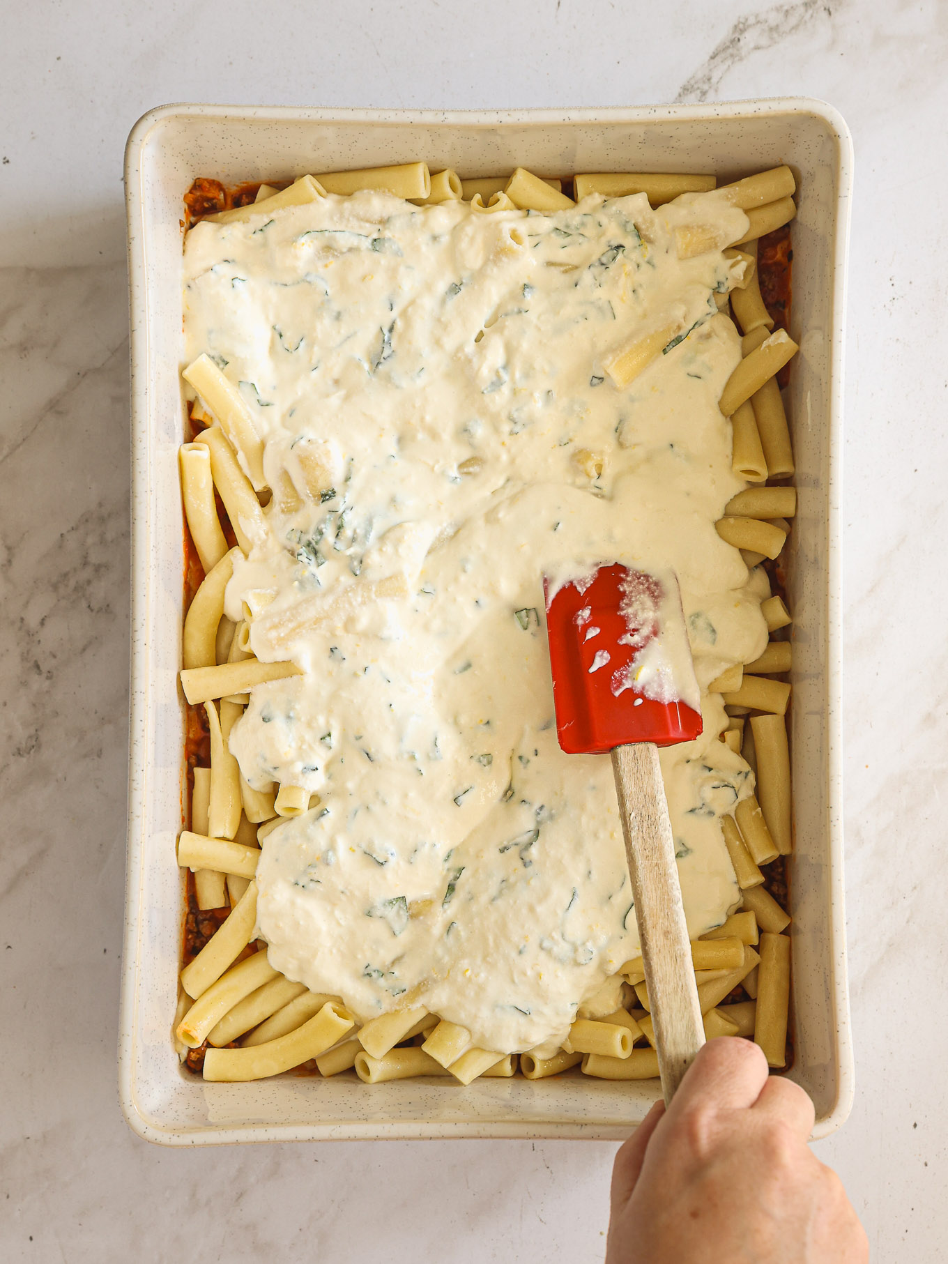 ricotta mixture over cooked ziti pasta in a baking dish.