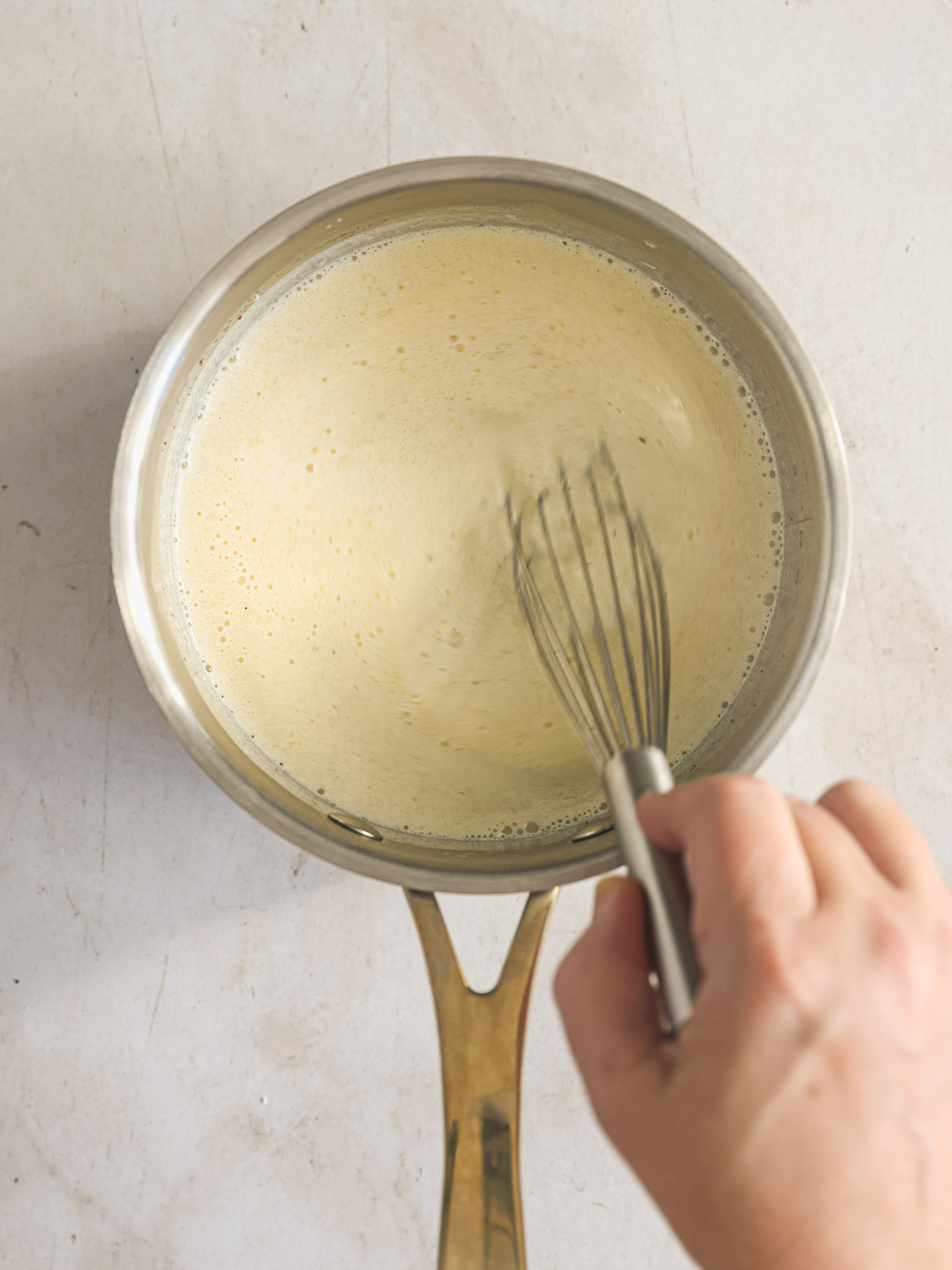 alfredo sauce whisked in saucepan.