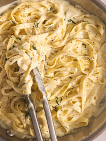 fettuccine tossed with homemade alfredo sauce in pan.