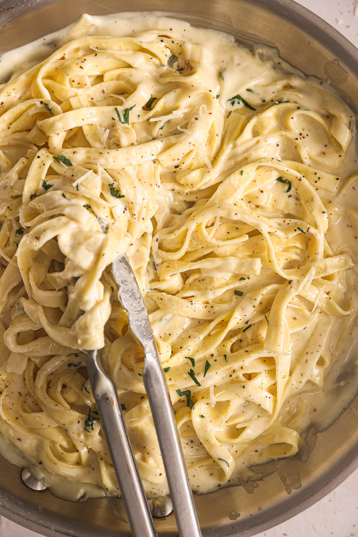 fettuccine tossed with homemade alfredo sauce in pan.
