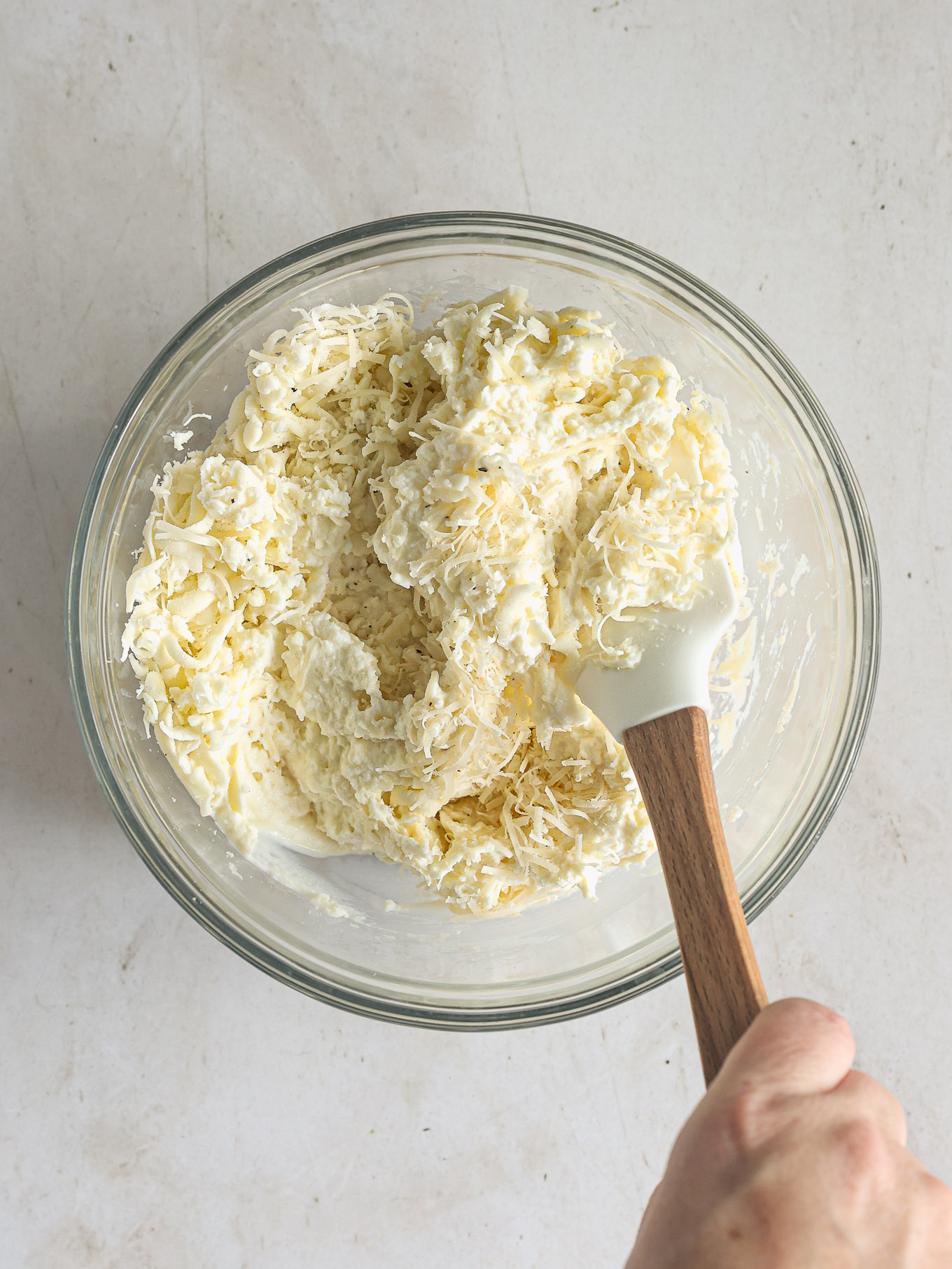 ricotta with shredded cheese in a mixing bowl.
