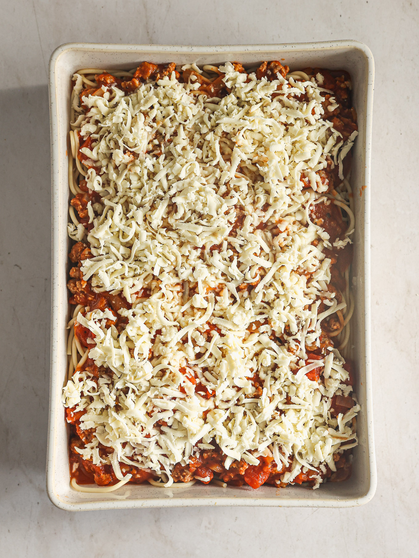 spaghetti casserole topped with shredded cheese.