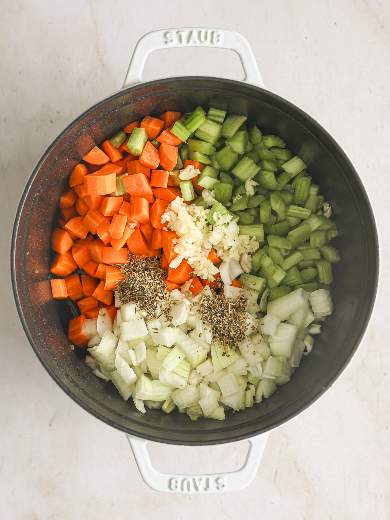 onions, celery, and carrots with spices in a soup pot.
