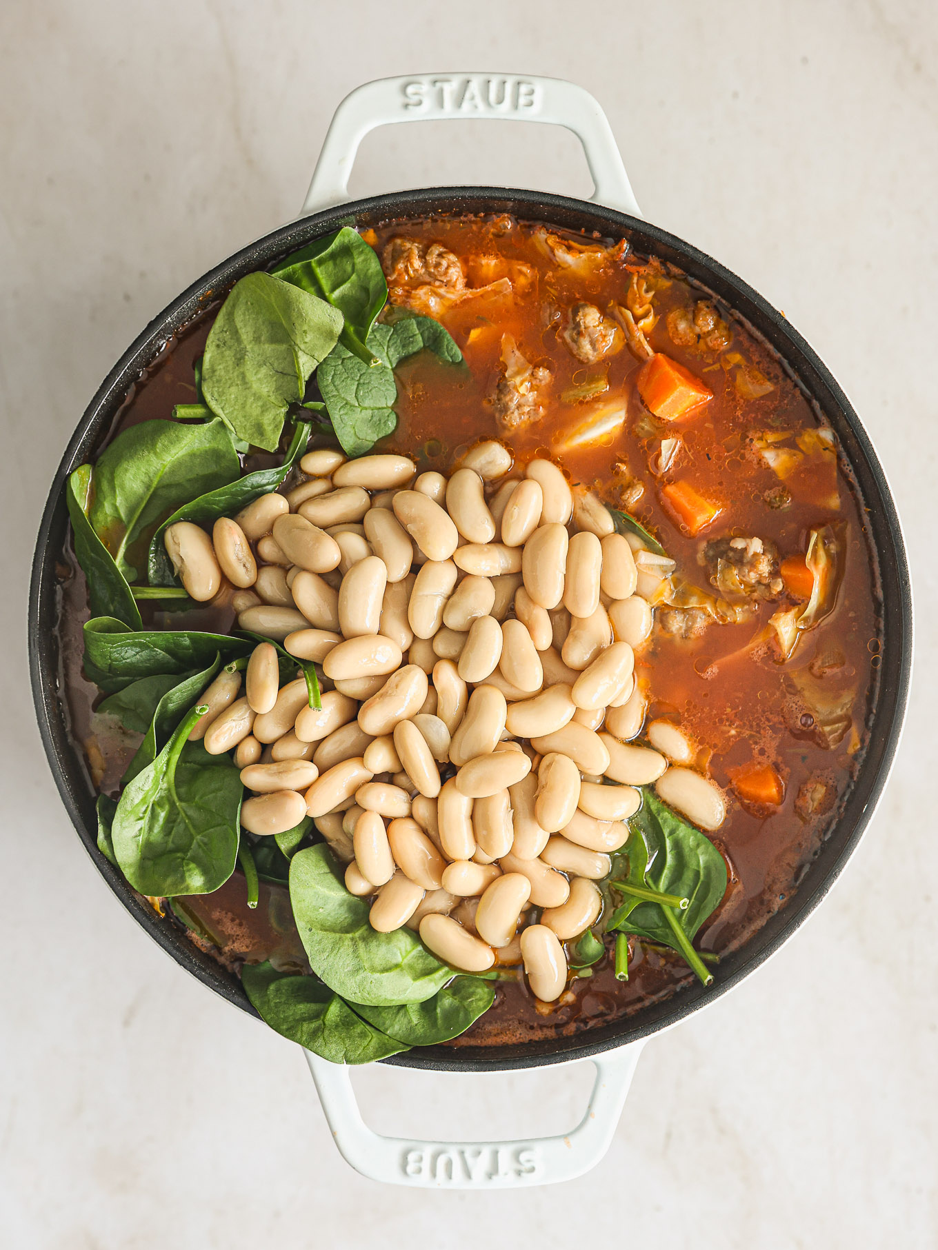 spinach and beans in a soup with sausage and cabbage.