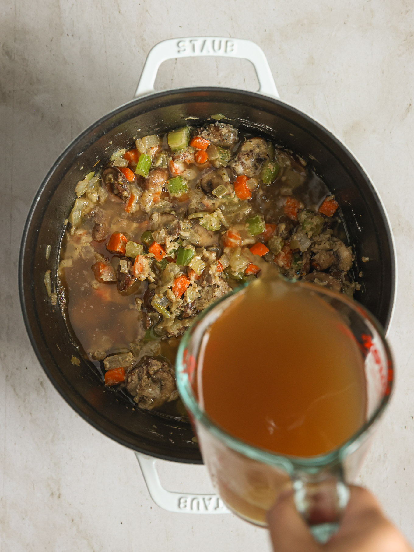 chicken broth pouring over cooked vegetables.