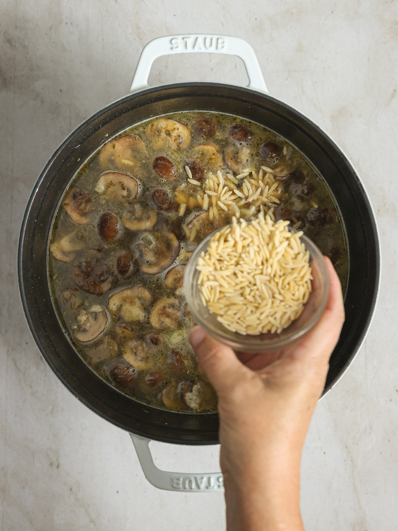 orzo going into a soup pot.