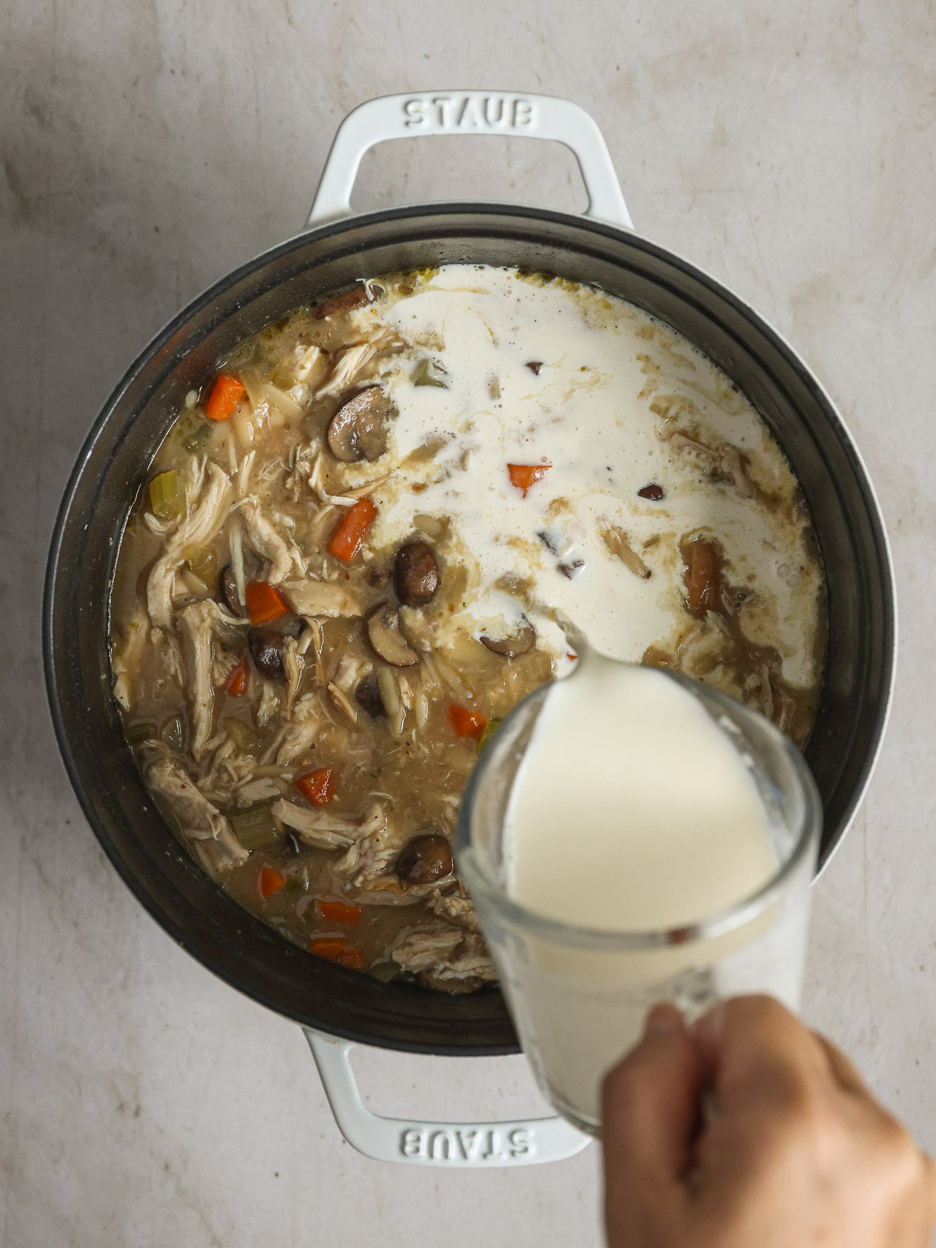 cream going into a soup pot.
