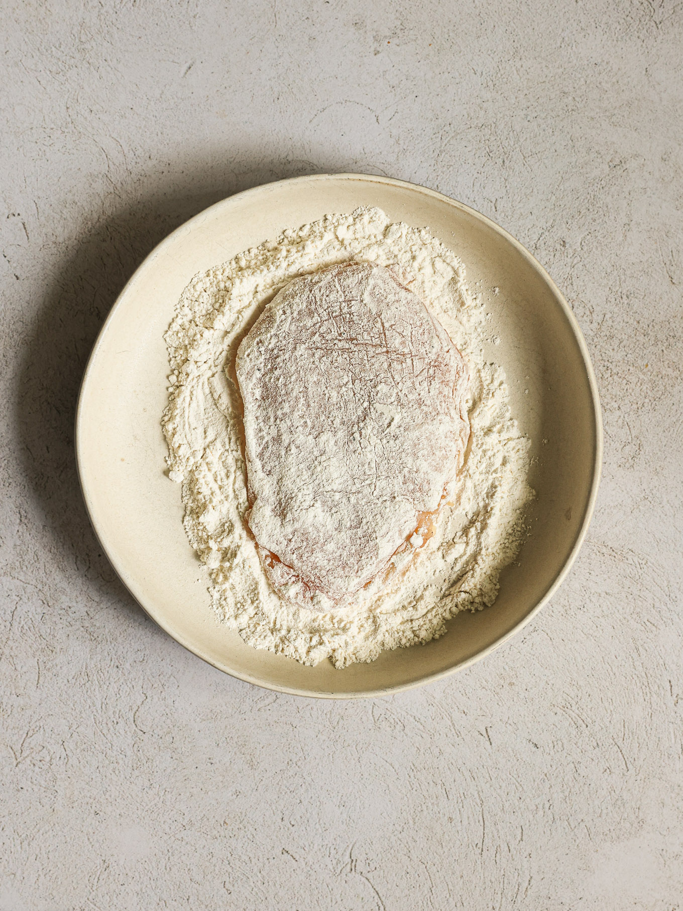 chicken breast drenched in flour.