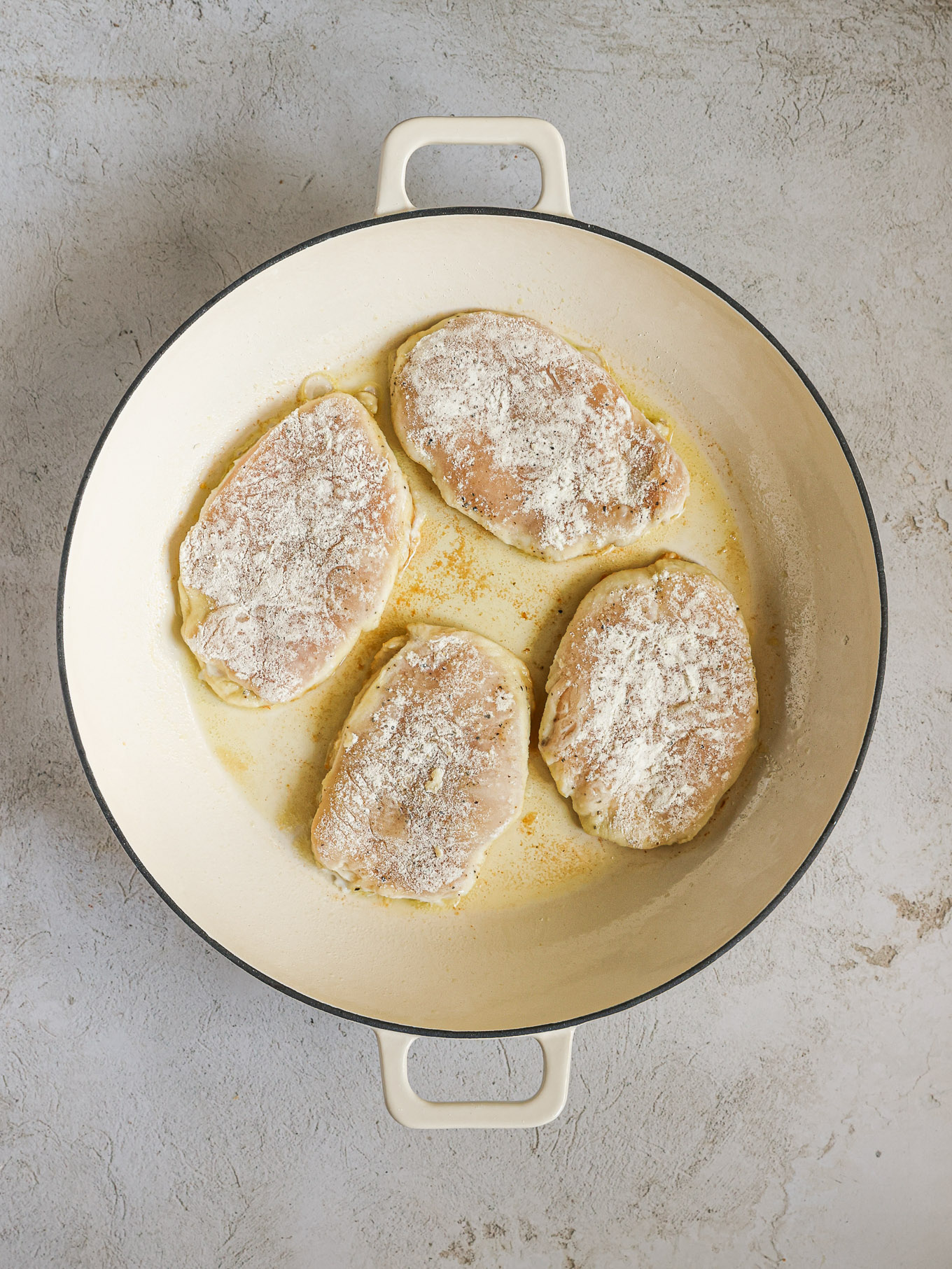chicken breast cooking in a skillet.