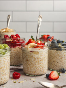 prepared overnight oats topped with fruit in glass jars.