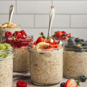 prepared overnight oats topped with fruit in glass jars.