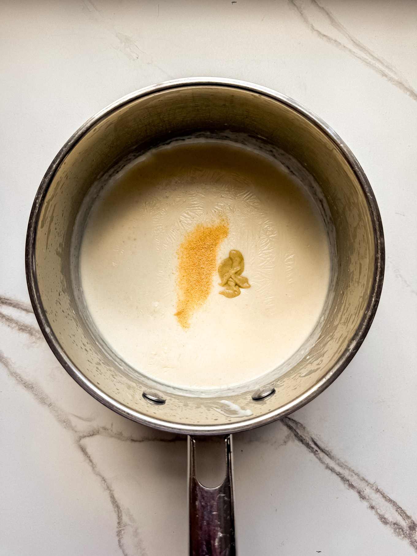 mustard and spices in a saucepan with cream.