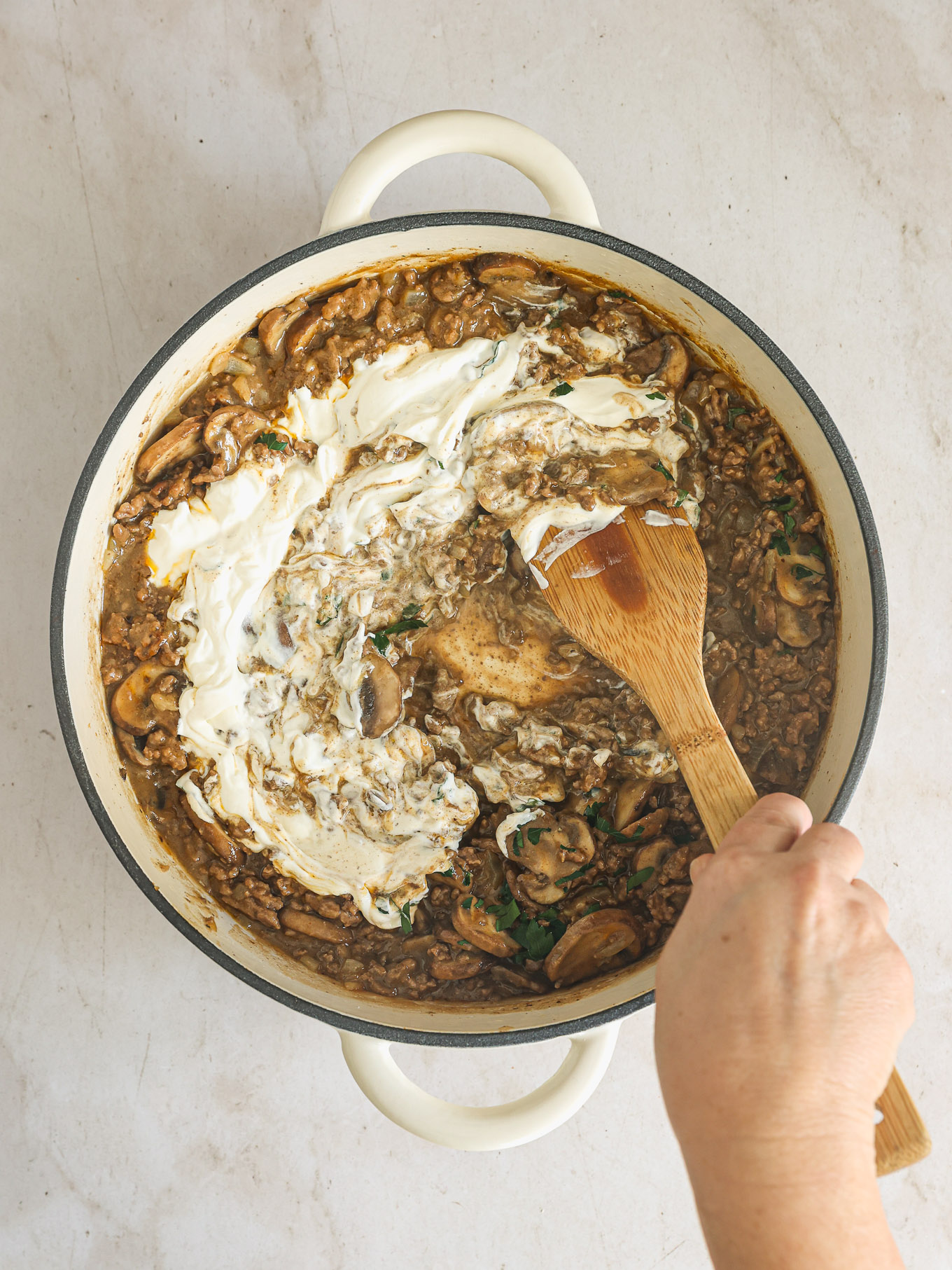 sour cream with cooked mushrooms and beef in a skillet.