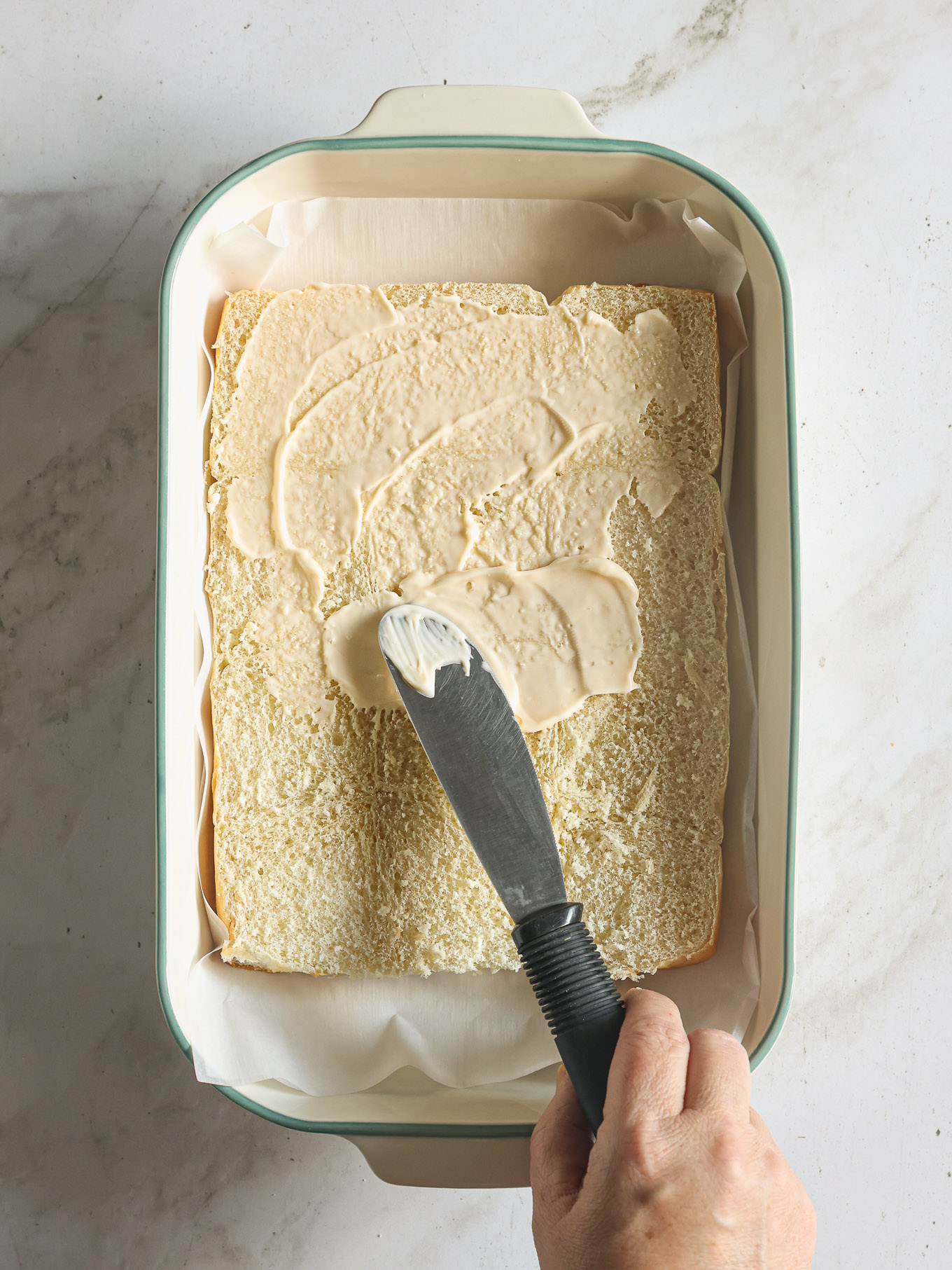 mayonnaise spread on the bottom half of sliced hawaiian rolls.