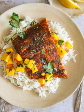 blackened salmon over rice and mango salsa in a bowl.