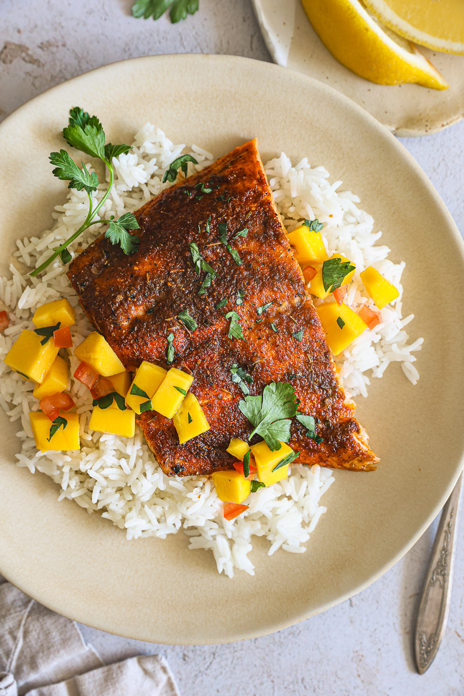 blackened salmon over rice and mango salsa in a bowl.