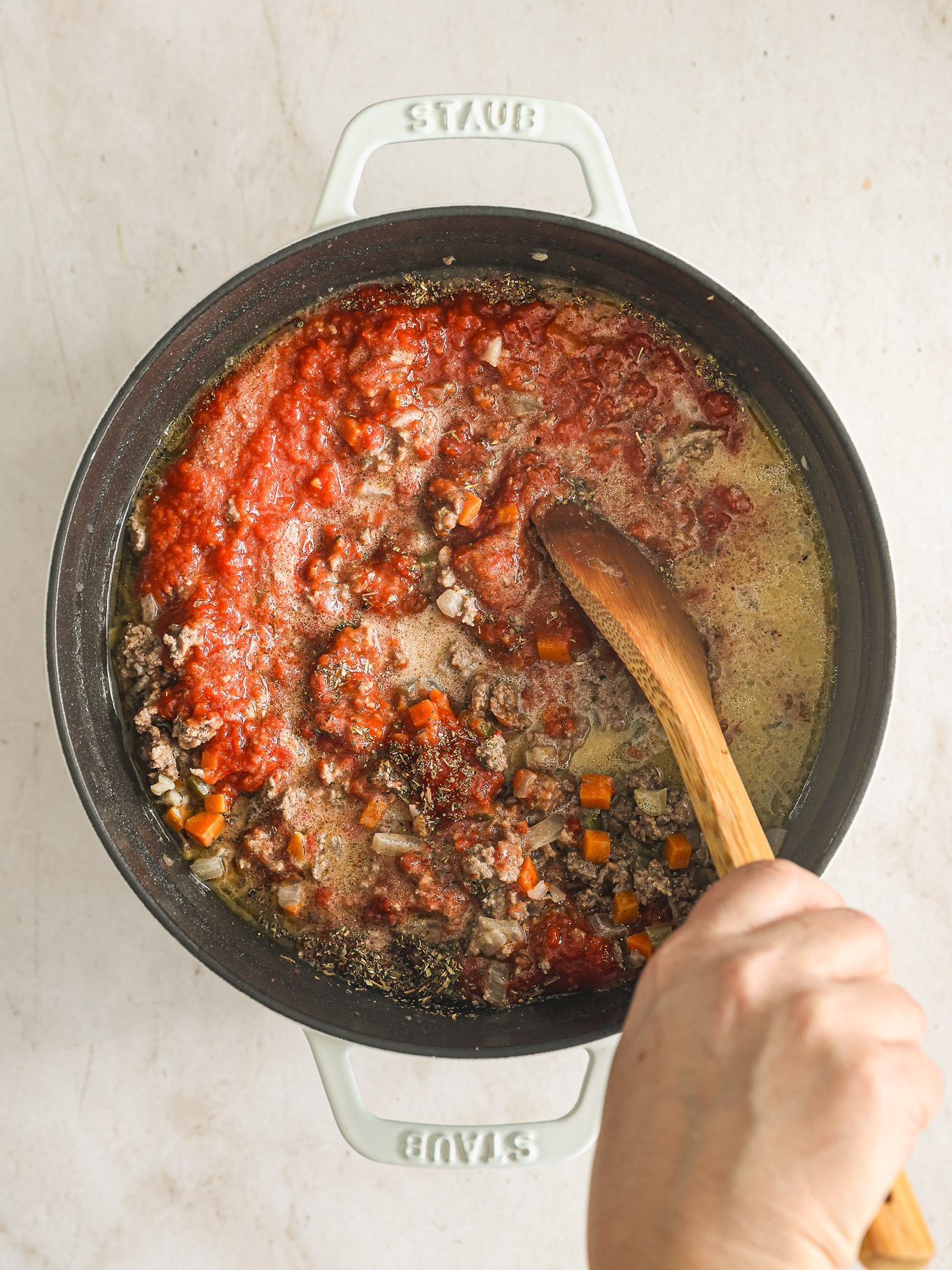 meat sauce in dutch oven with wooden spoon.