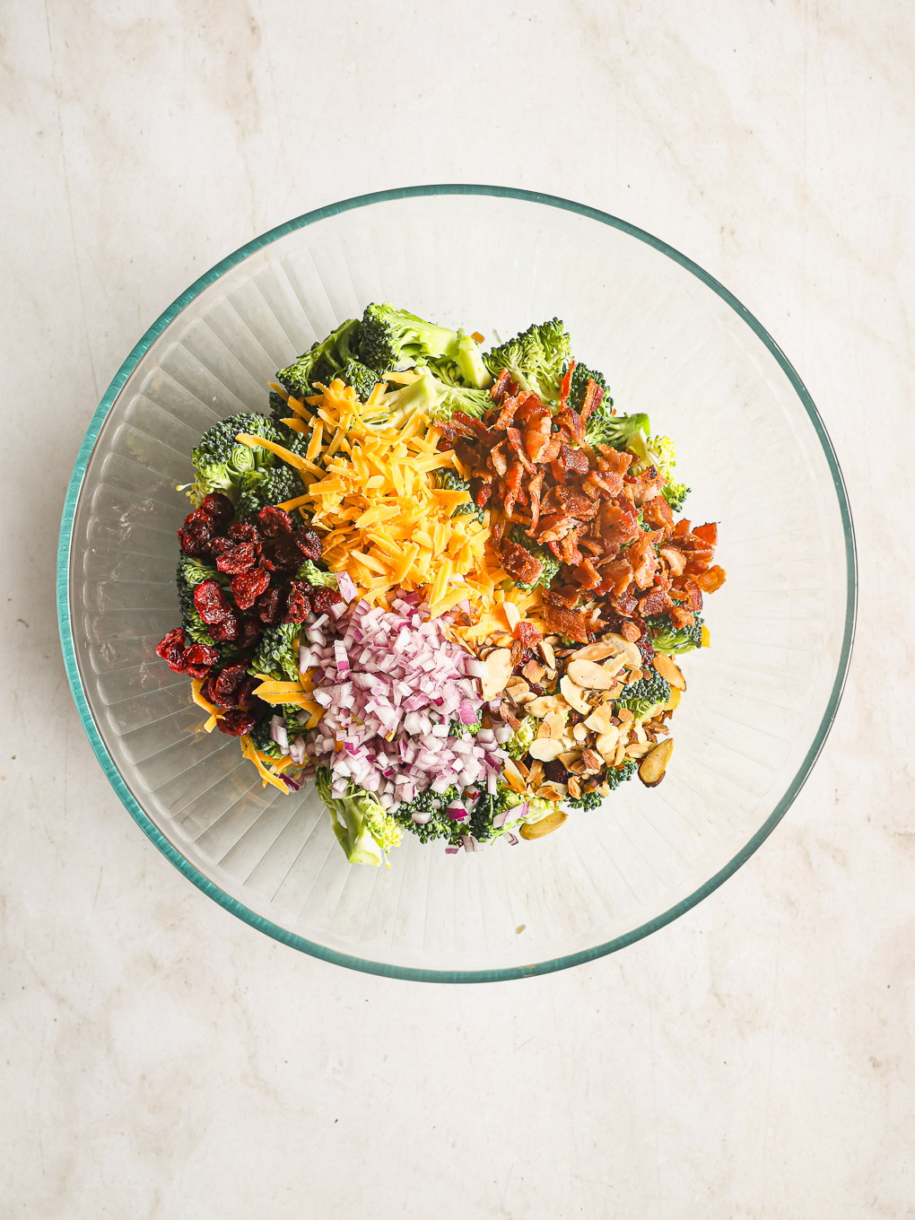 prepared ingredients in a glass bowl for broccoli salad.