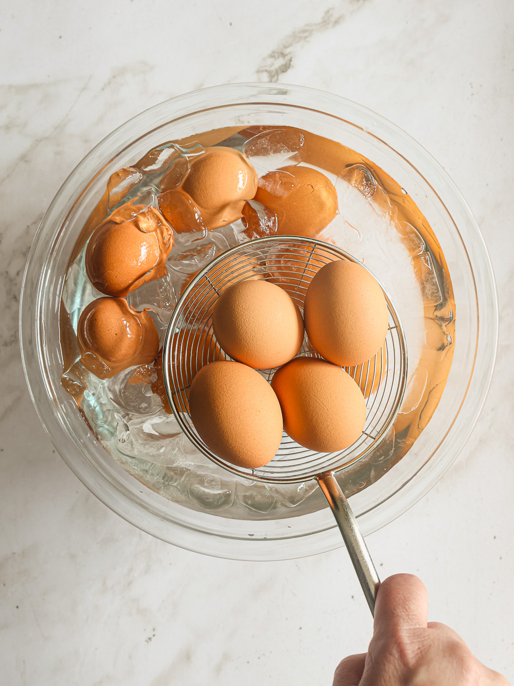 hard boiled eggs going into an ice bath.