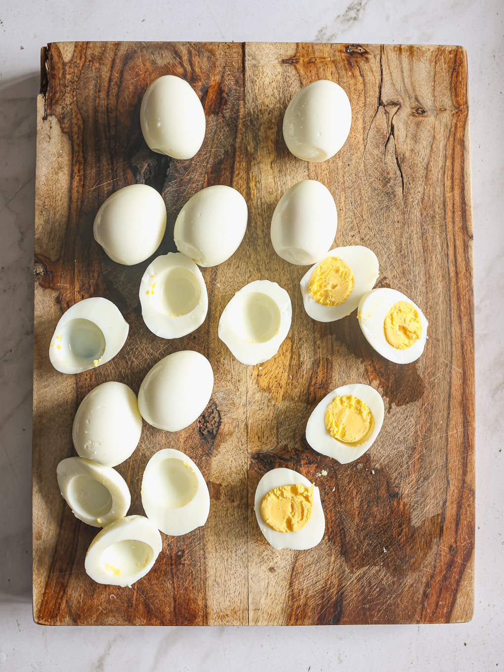 peeled and halved hard boiled eggs on a cutting board.