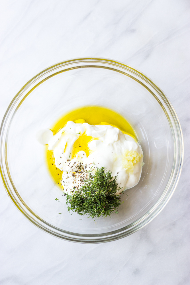 yogurt with herbs in oil in a glass bowl.
