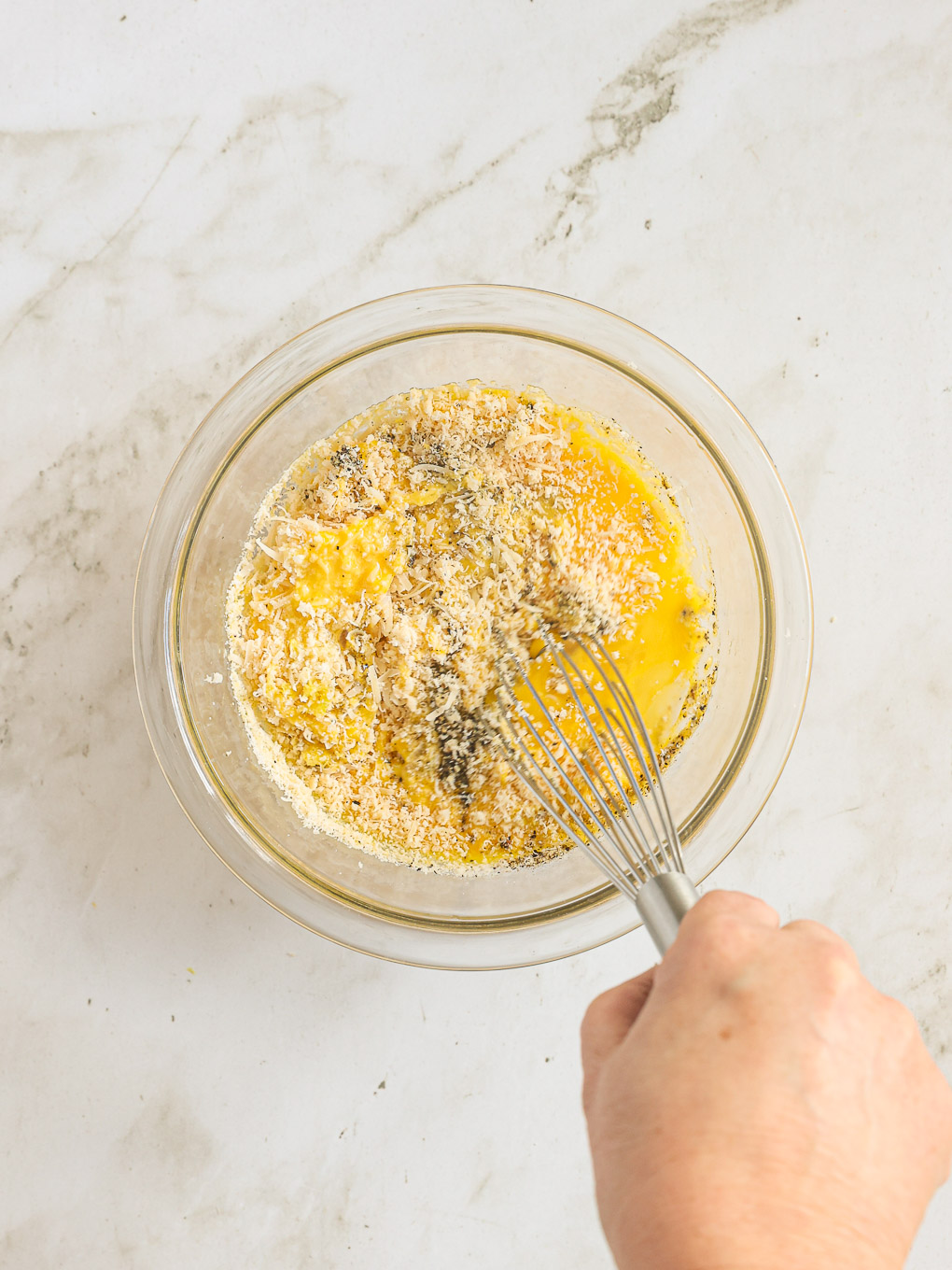 whisked eggs with parmesan in a glass bowl.