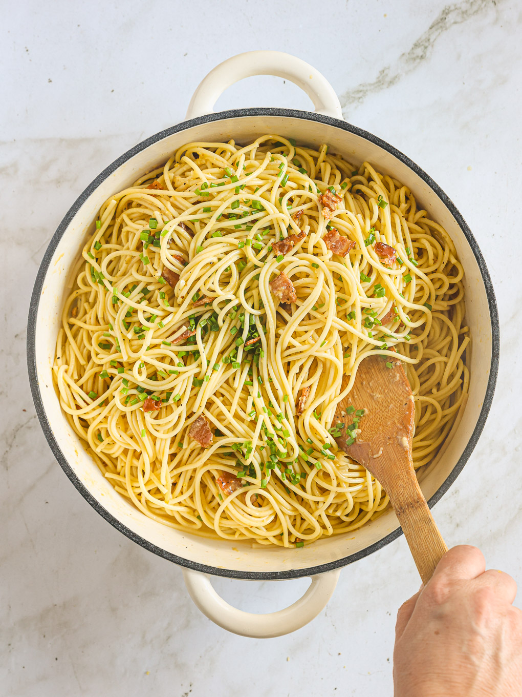 tossed spaghetti with fresh herbs in a pan.