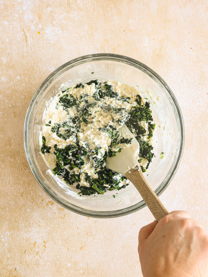 frozen spinach with cream cheese and cheese in a glass bowl.